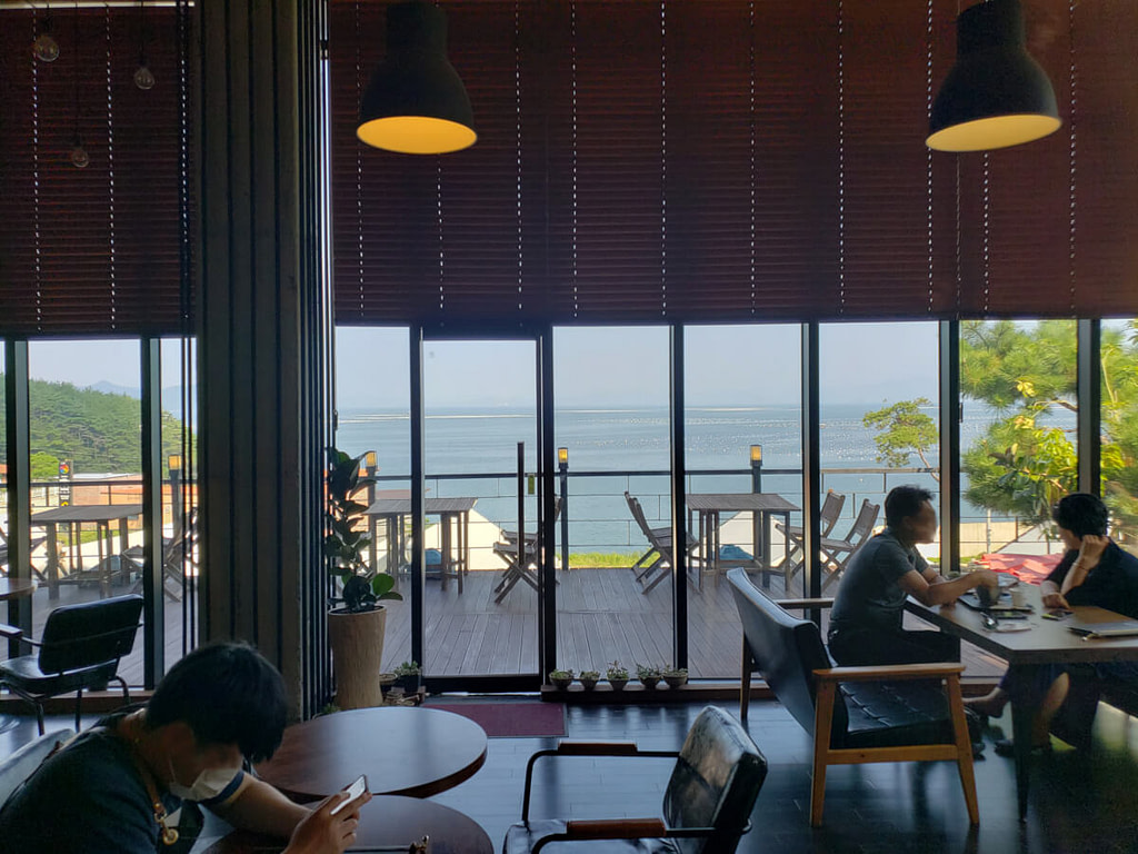 People sitting at tables along window overlooking seaside view
