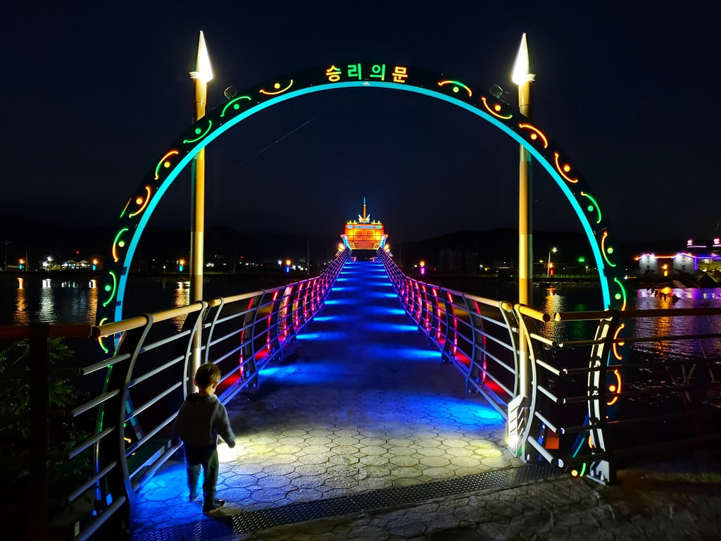 The illuminated archway entrance to a pedestrian bridge at night