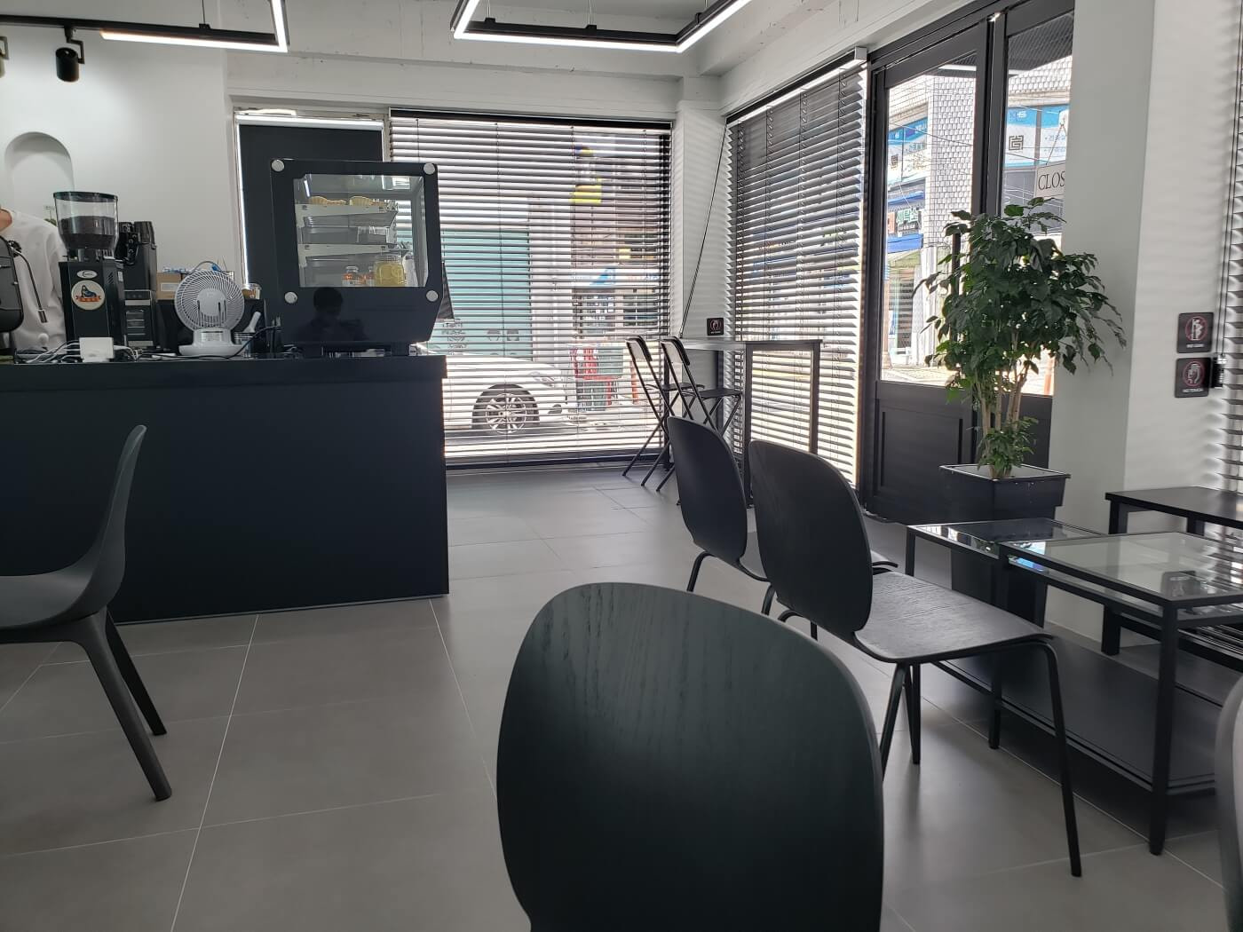 Blinds on windows with white walls and black chairs inside café
