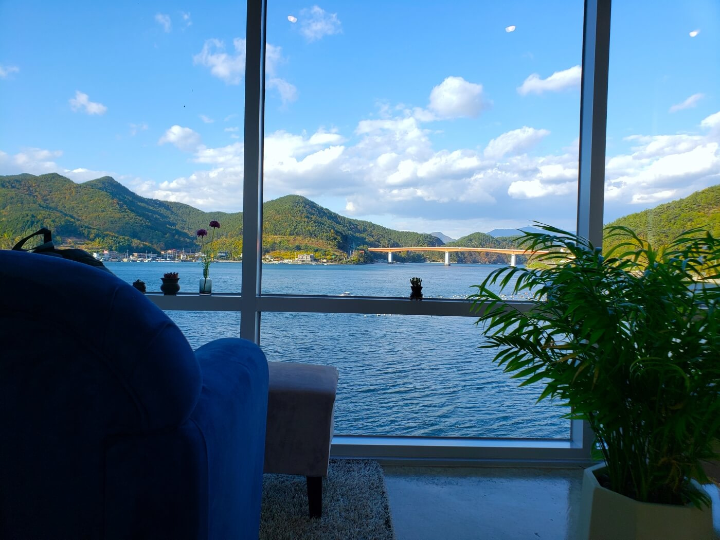A blue couch and potted plants facing a large window with a sea view at An Café