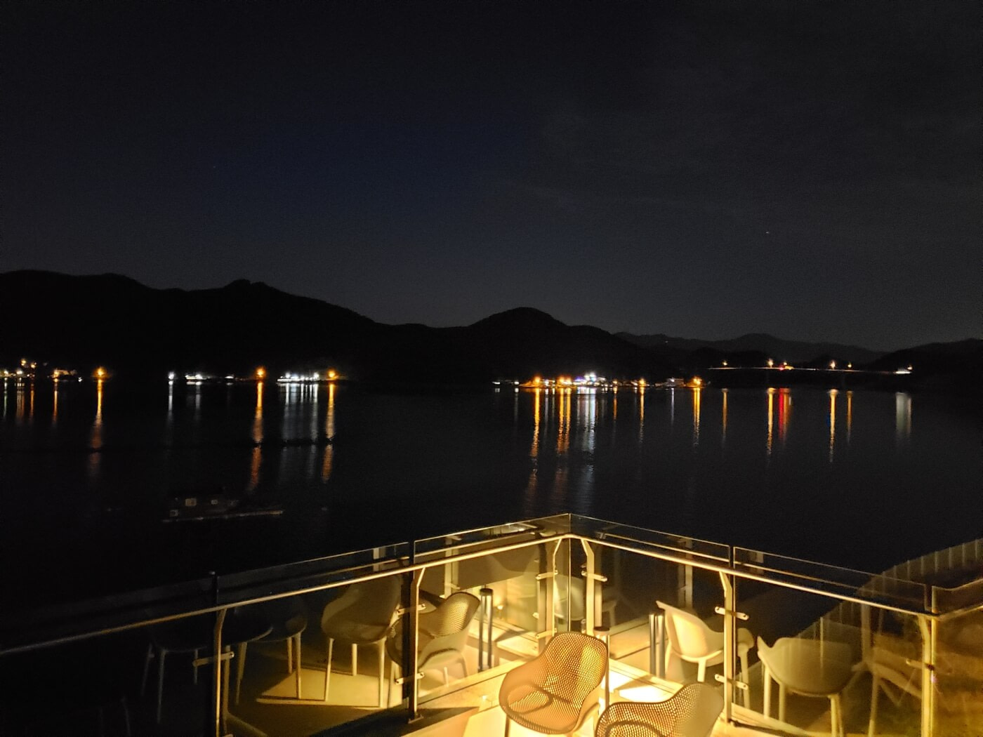 Lights reflecting off the water viewed from a café at night