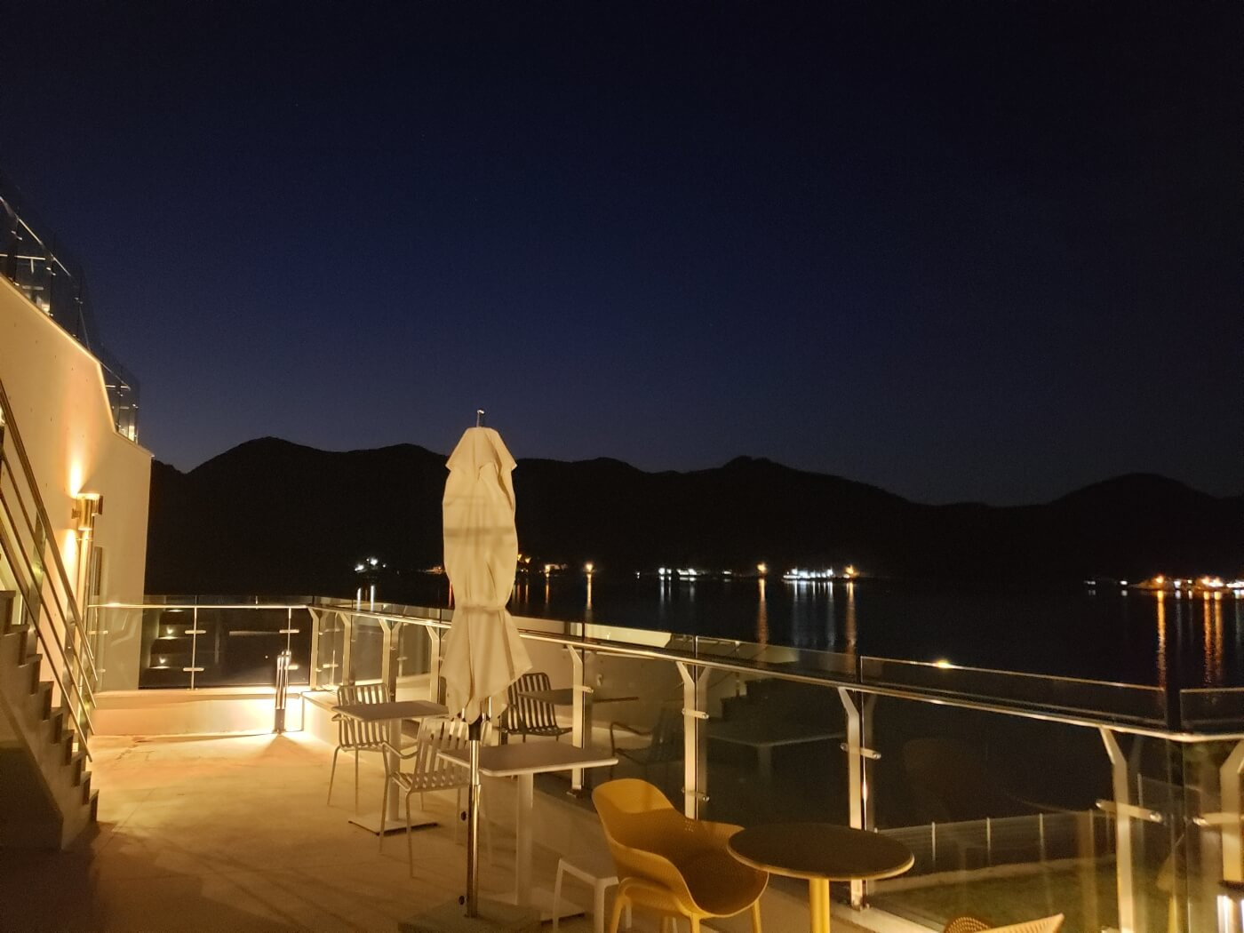 Outdoor tables overlooking the sea and mountains at night