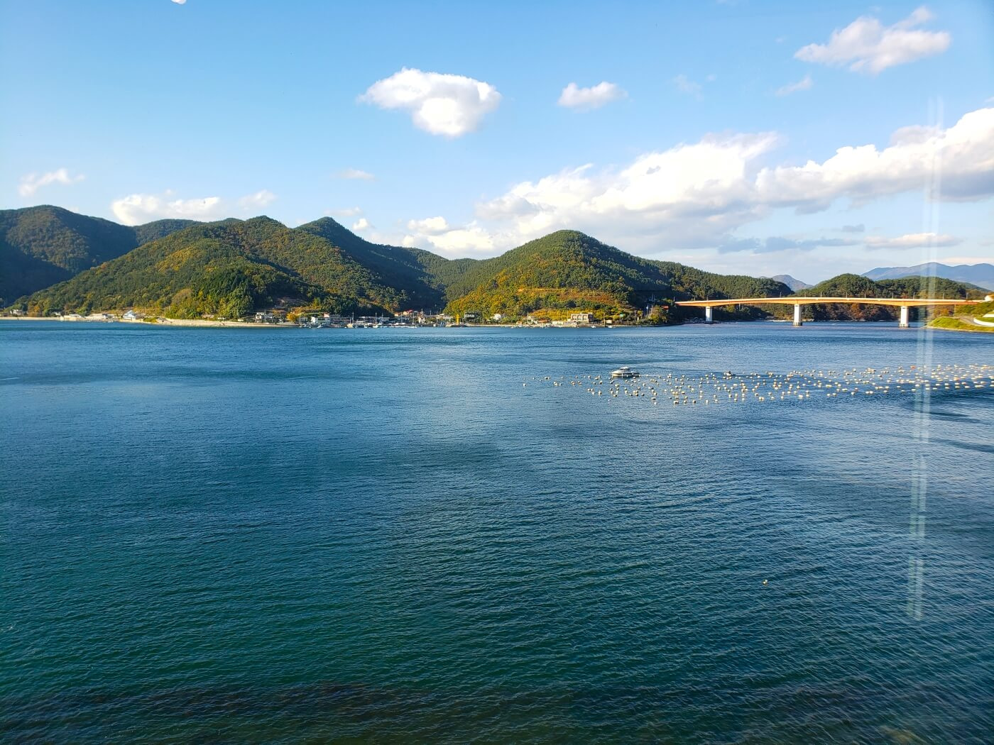 Turquoise water and an orange bridge with mountains in Goseong, South Korea