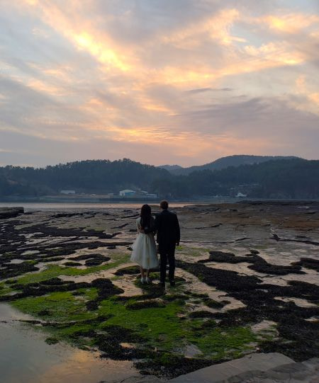 Nate and Alice's wedding photo in Goseong, Gyeongnam, Korea facing a sunset on the rocks and water