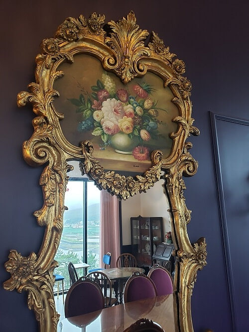 A large, ornate mirror on the wall with a golden frame