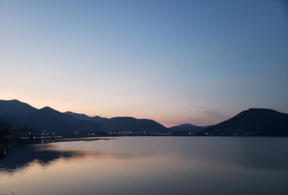 Daega Reservoir at sunset with still waters against mountains