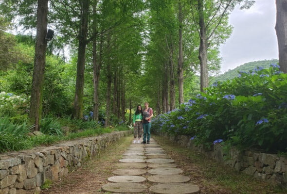 Nate and Alice with Noah standing between two rows of trees at Grace Garden