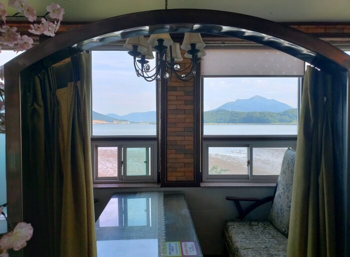 A table booth behind a curtain along a window with a view of the sea