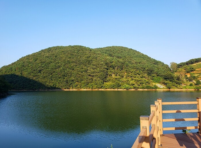 A calm reservoir at a boardwalk facing a mountain