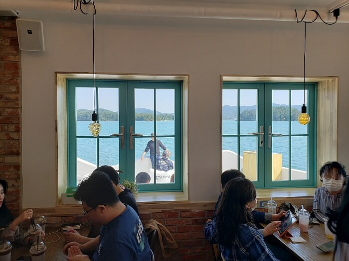 People sitting inside along the window with a nice view of the water