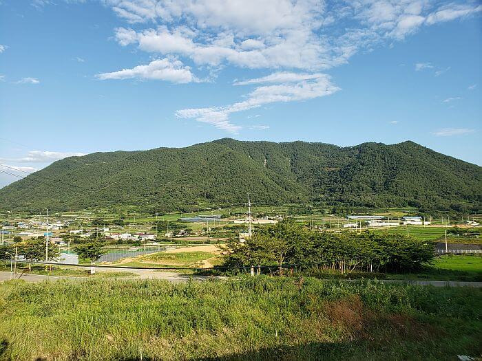 A view of a small village and a few fields at the base of a mountain