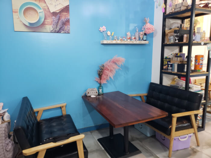 A table along a bright blue wall inside Dangdong Bakcine Coffee with a pink chandelier