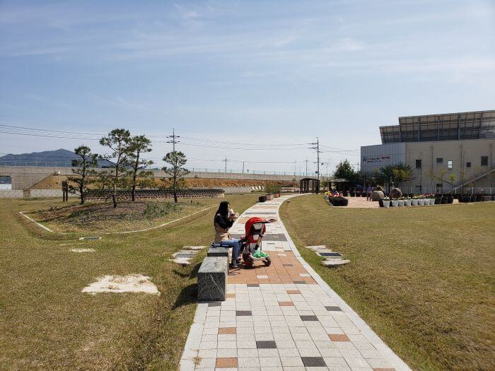 Alice sitting on a stone bench with Noah in the stroller