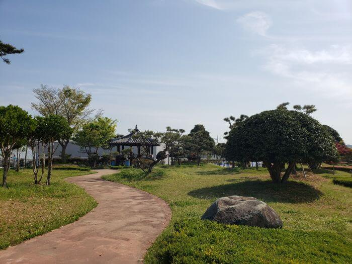 Path through the grass with a small pavilion and scattered trees