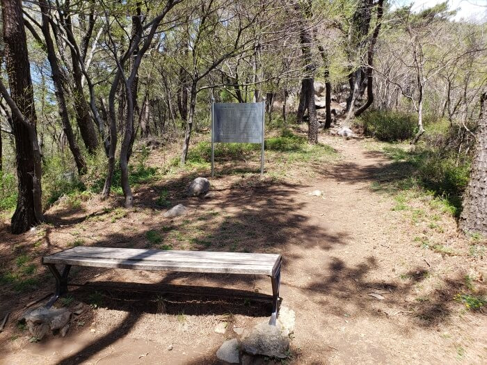 A bench in front of a signpost about the Goseong Fortress Wall