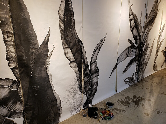 A white wall painted with black large leaves in the art gallery and studio