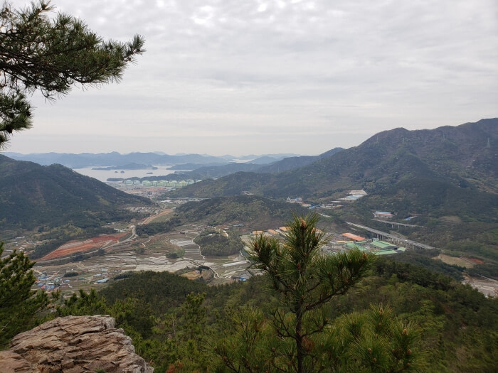 View of the sea, islands, towns, and other mountains from the first lookout area with a large rock as a platform