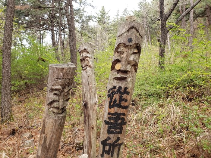 Carved, wooden poles of faces with some Chinese characters