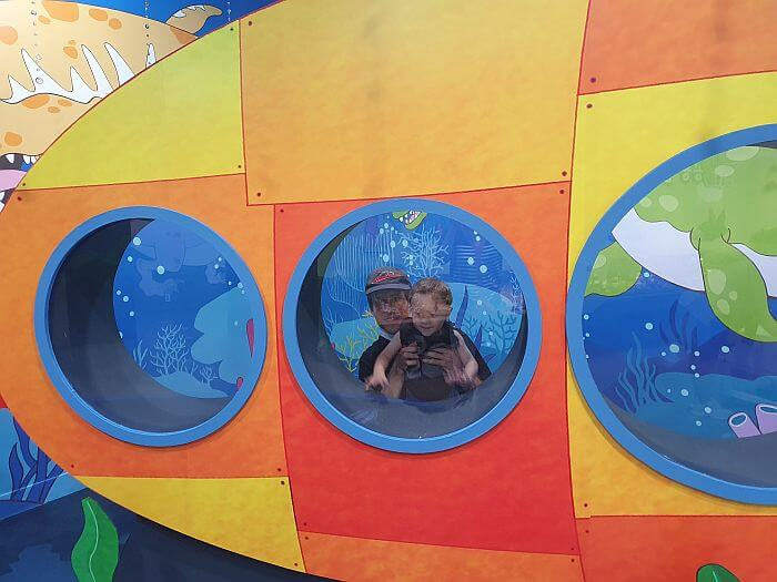Baby Noah and Nate behind a window in an underwater photo zone