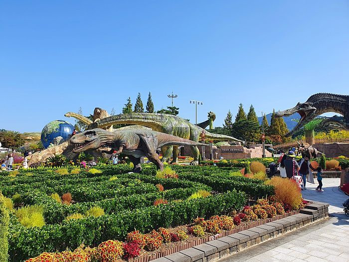 Dinosaur figures among bushes and flowers outside