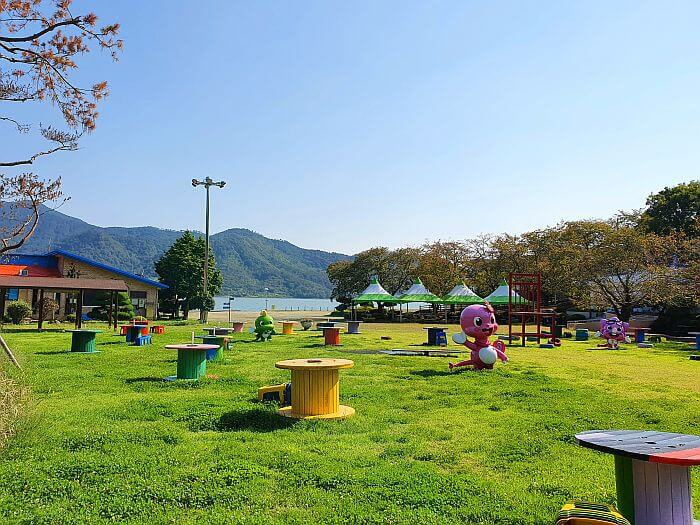 A grassy playground with colorful, scattered items including spools