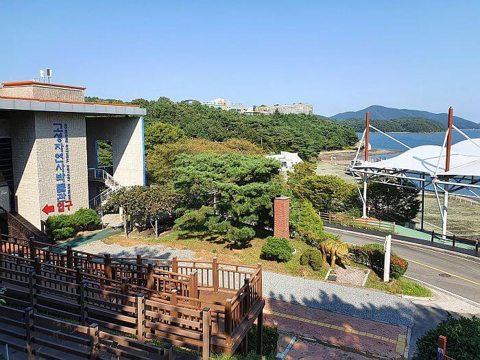 A wooden deck and stairs across from the Goseong Natural History Museum with a view of the sea