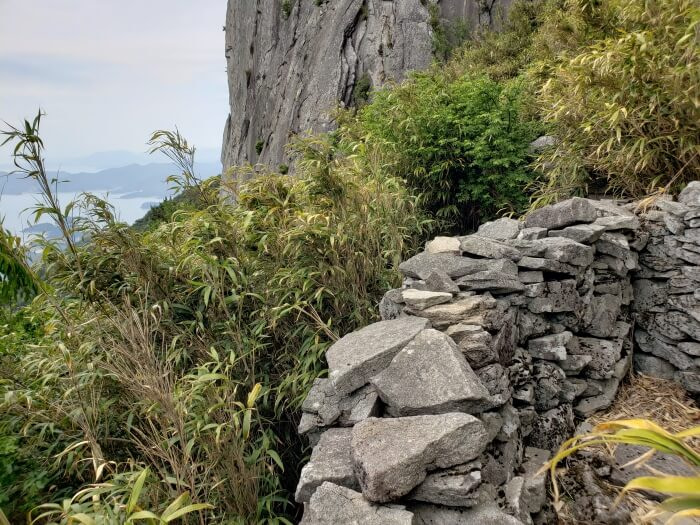 A corner of a wall of stacked rocks against a cliff showing the inside of the wall