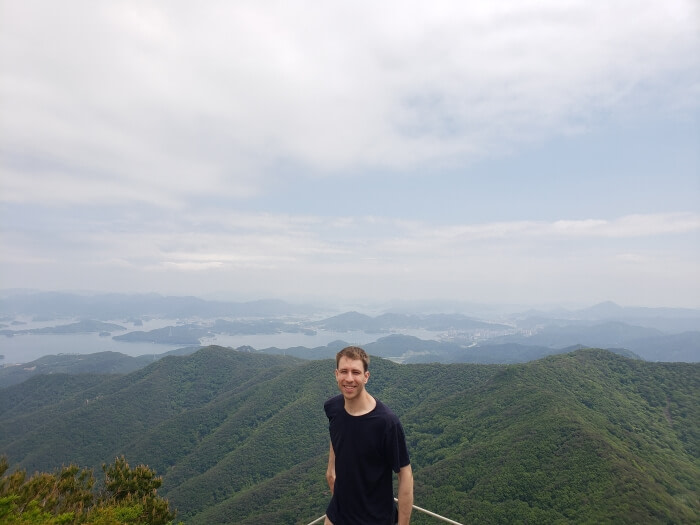 Mate standing on Byeogbangsan peak with green mountains in the background