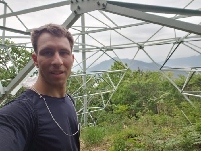 Nate standing under an electrical tower