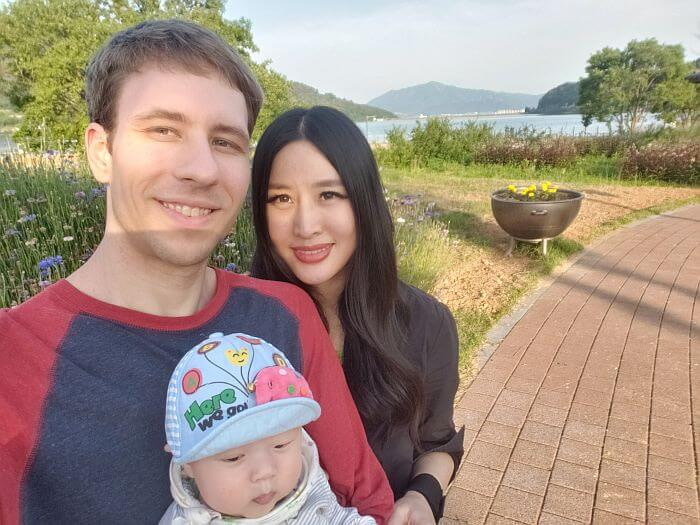 Nate, Alice, and Noah on a brick path next to a wildflower patch with the sea and mountains in the background
