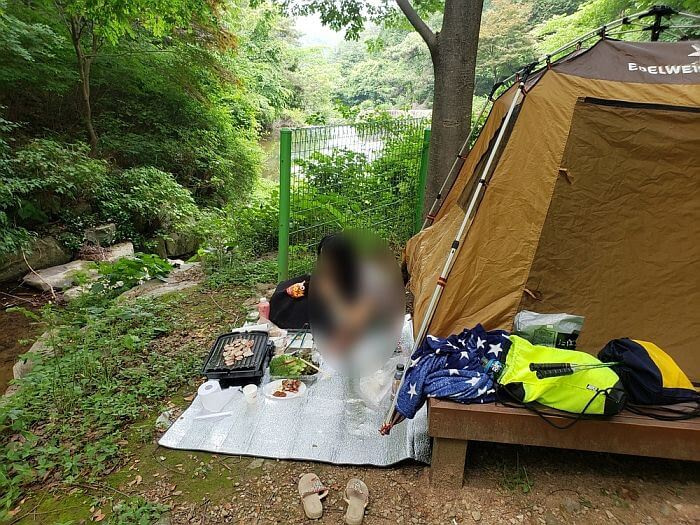 Grilling on a matt next to a tent
