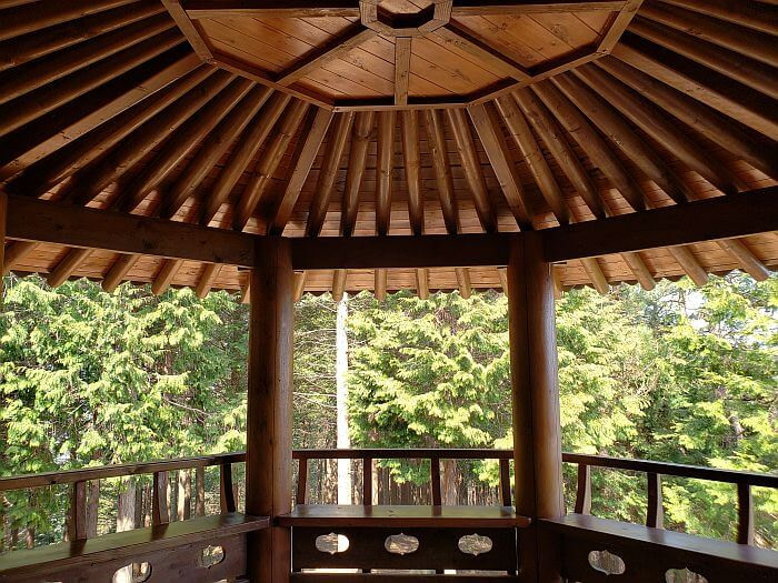 A wooden pavilion surrounded by conifers