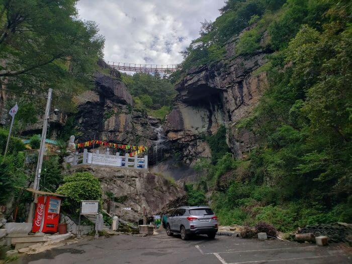 Car parked under a bridge next to a rocky waterfall