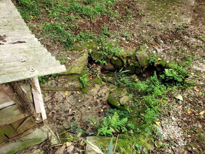 Mossy rocks in front of a small structure