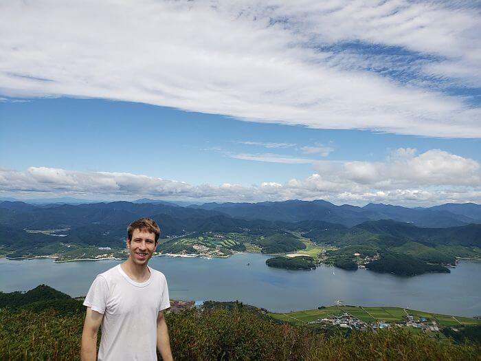 Nate standing in front of a nice view of water, towns, and mountains below