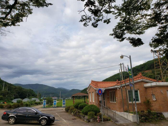 A town hall building next to a rice field and mountains