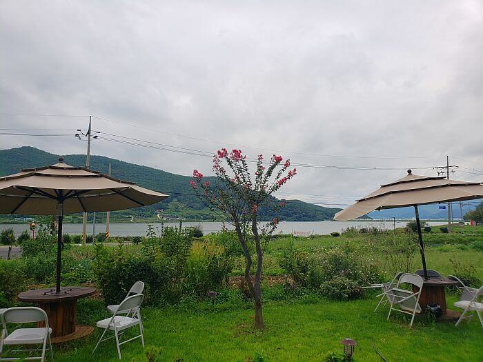 Umbrellas above tables and chairs outside facing Daega Reservoir at Daehuijae Café