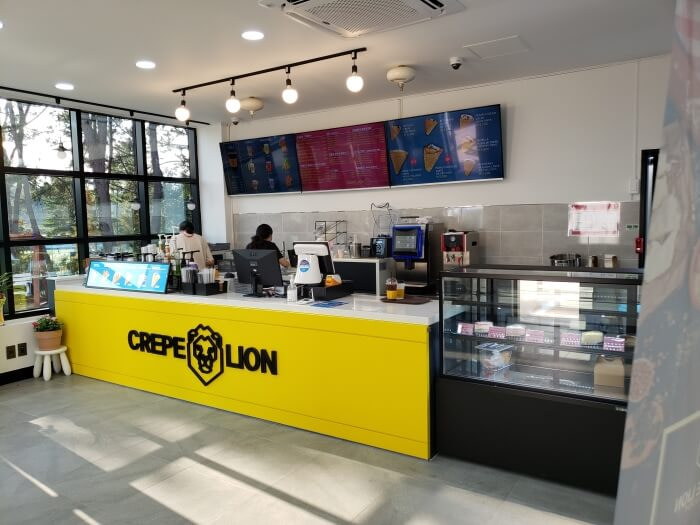 Crepe Lion ordering station with their yellow logo displayed under the counter
