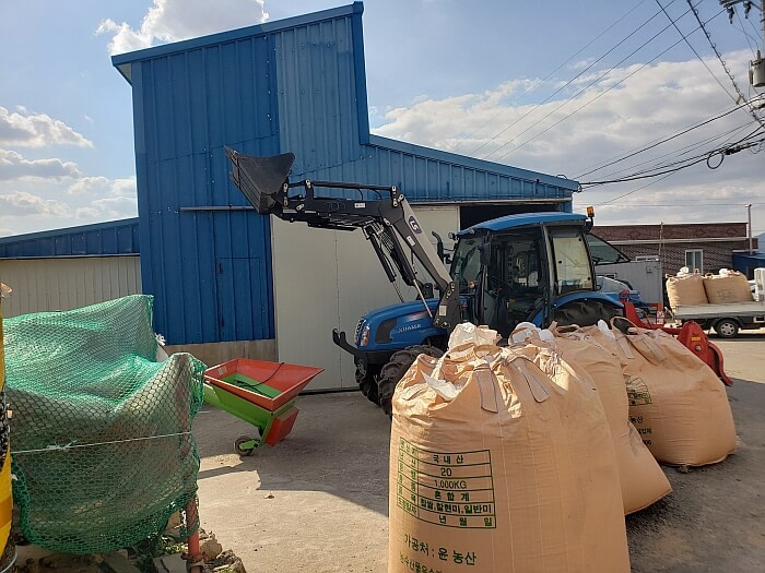 1000 kg bags of rice on a driveway next to a tractor