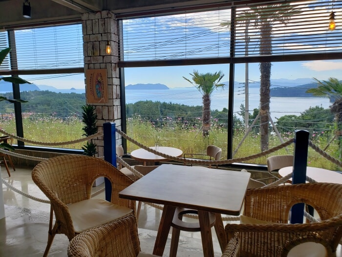 A table and chairs next to a large window with a sea view