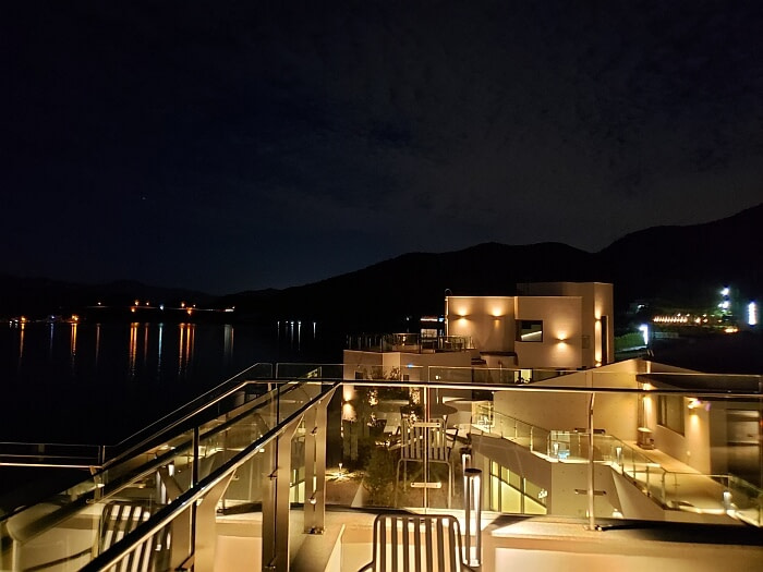 Café along water with lots of outdoor seating and lights at night