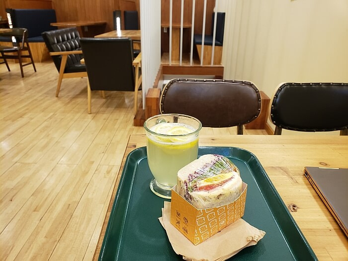 A sandwich and a glass of lemon tea on a tray