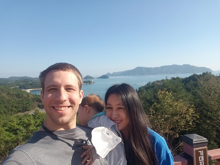 A family photo with baby Noah in front of a view of the sea and islands