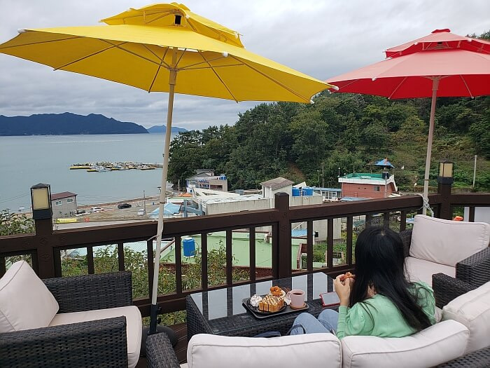 A family sitting on a sofa outside enjoying refreshments and a view of the sea
