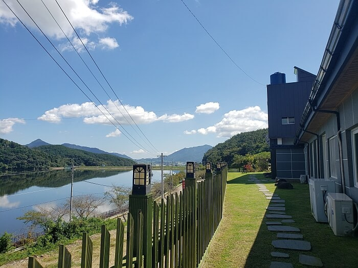 The grassy yard of a café viewing Daega Reservoir and mountains
