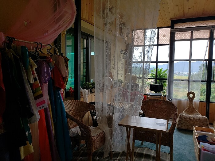 A room with wicker furniture and traditional Korean hanbok clothes with a village view out the window
