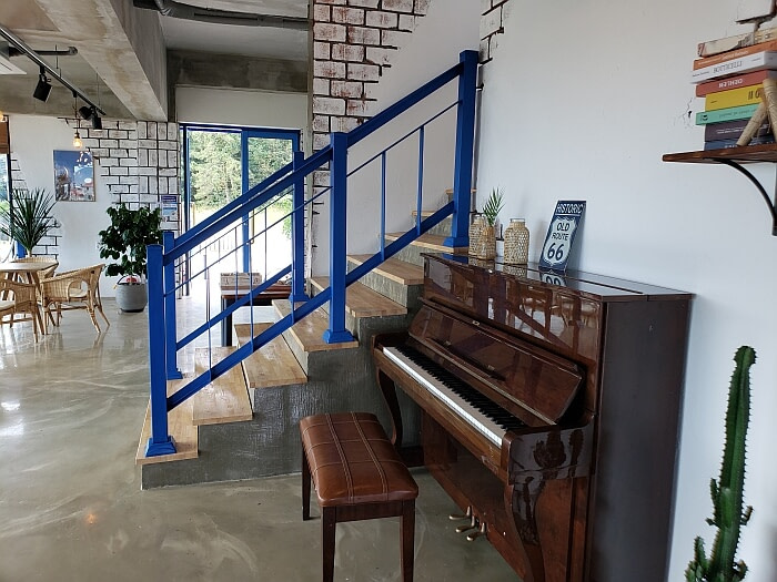A piano on the first floor of a café next to some stairs