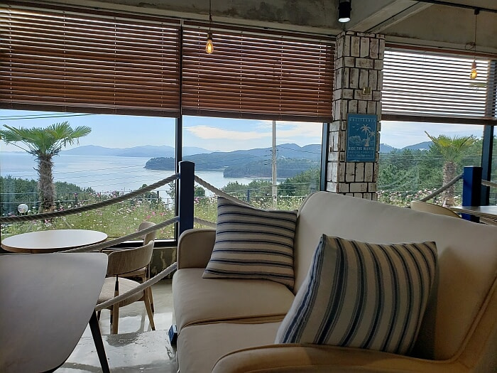 A sofa with pillows in a café with a nice view of the sea