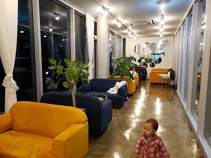 A row of soft couches along a wall of windows inside An Café