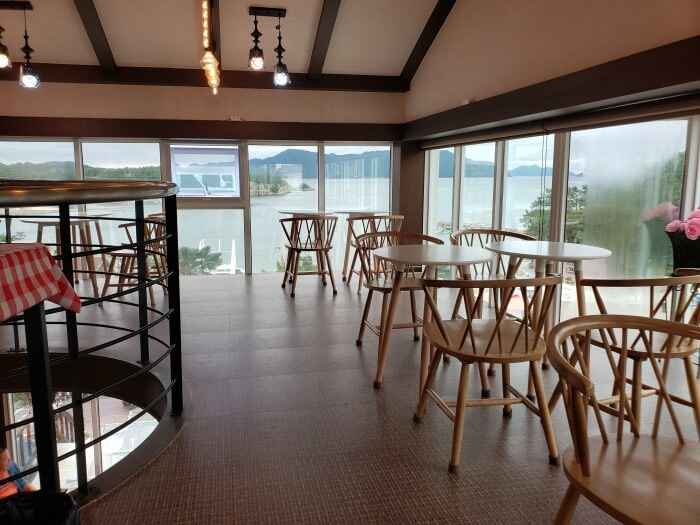 Tables and chairs on the second floor of a café along windows with a sea view
